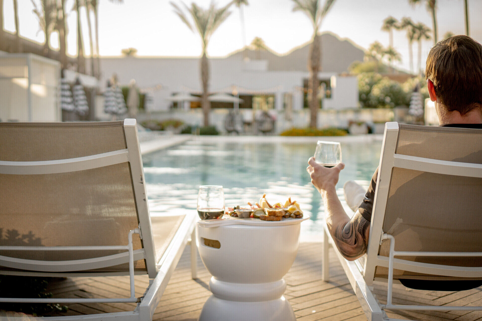 person lounging by pool with wine